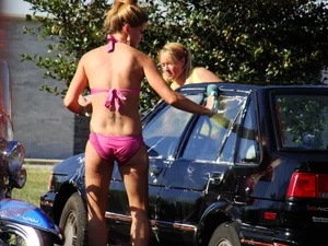 Group of cute girls at a car wash in bikinis and shorts