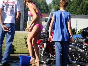 Group of cute girls at a car wash in bikinis and shorts