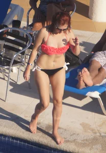 Sexy red haired girl in pink and black bikini at the pool
