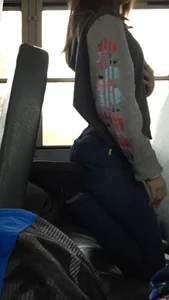 Young Girl in Jeans Standing on One Leg in a Bus