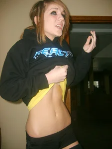 Skinny candid teen pulling up her T-shirt showing off her flat abs