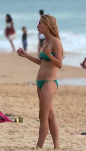 Sexy brunette in thong bikini and blonde friend in green bikini at the beach