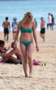 Sexy brunette in thong bikini and blonde friend in green bikini at the beach