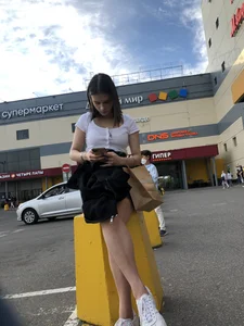 Extremely Cute Girl Sitting With Crossed Legs on a Parking Lot