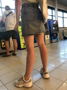Young Candid Girl With Slim Pale Legs In a Denim Skirt Waiting in the Queue