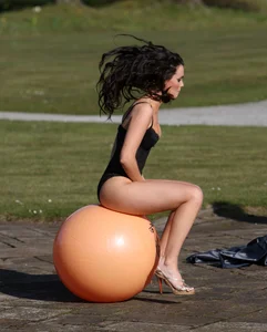 Girl in High Heeled Shoes and a Body Bouncing on a Fitness Ball Outdoors Creepshot