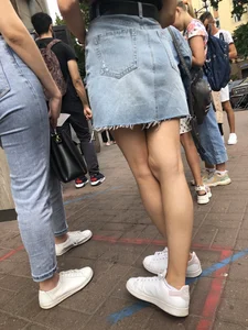 Hot slim legs closeups, street girl wearing a denim fringed skirt