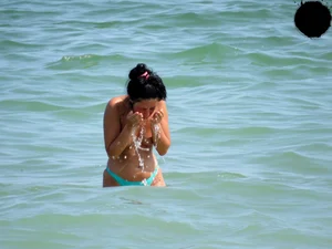 Brunette topless babe with cute tits and a nice ass in a thong bikini