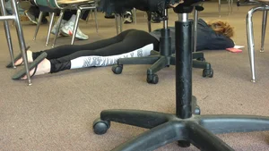 Teen in Slippers and Tights Lying on the Floor in College Classroom