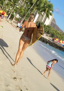 Skinny blonde surfer on the beach in little bikini