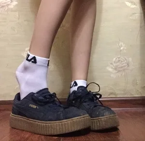 Skinny Feet in White Socks and Sneakers Half Taken Off Closeup Photo