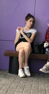 Girl in Shorts abs Sneakers Sitting With Crossed Legs on the Street Bench Creepshots