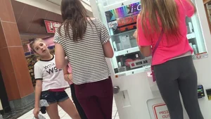 Little blonde teen in grey leggings at the mall with her friends