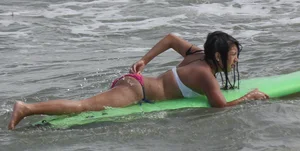 Brunette bikini girl on the beach and surfing in her bikini