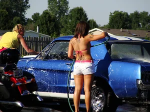 Group of cute girls at a car wash in bikinis and shorts