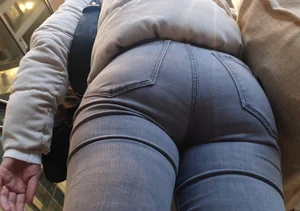 Girl with a tight ass in grey jeans going up the escalator