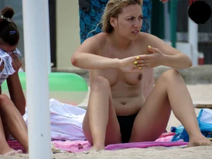 Topless blonde babe on the beach with a big booty in a black thong