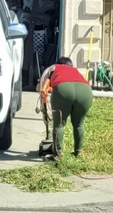 Mature milf in green yoga pants bending over while mowing lawn