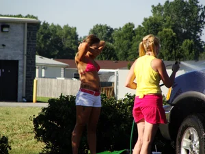 Group of cute girls at a car wash in bikinis and shorts