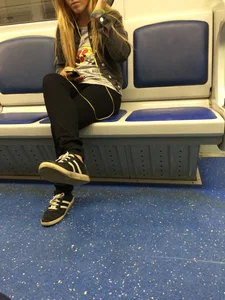 Girl in Tight Pants Sitting in a Subway Train with Her Legs Crossed Candid Photo