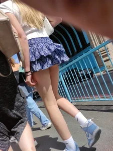 Skinny blonde girl wearing a short skirt with long slim legs street creepshots