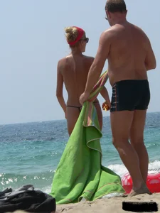 Topless skinny blonde lady in a g-string bikini at the beach