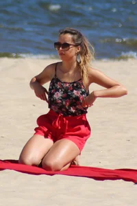 Hottie undressing from her red shorts to her bikini to layout on the beach