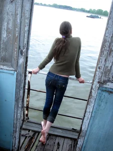 Girl in a Green Sweater and Tight Jeans Standing Shoeless by the Water Candid