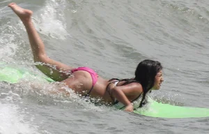 Brunette bikini girl on the beach and surfing in her bikini