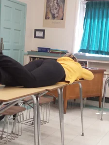 College teen in leggings lying on desk