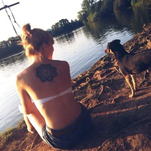 Tattooed girl sitting by the lake with a doggo
