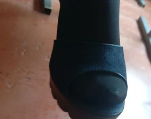 Young Girl's Foot in Black Pantyhose and a Sandal Under Table Closeup