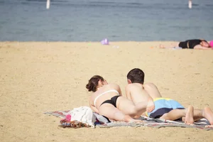 Sexy girl on the beach laying out and bending over in her bikini