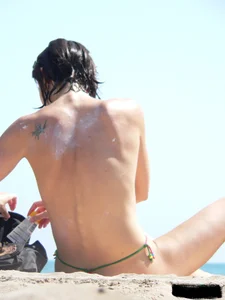 Topless beach milf looking sexy in a tiny g-string bikini