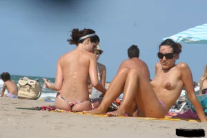 2 topless girls at the beach in thongs