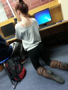 Skinny college teen girl in leggings and boots standing on her knees in class creepshot