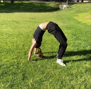 Skinny girl doing a gymnastic bridge in the park