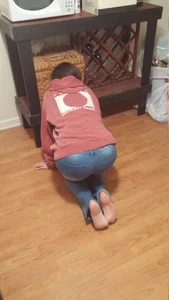 Barefoot girl in tight blue jeans doggy style on the floor