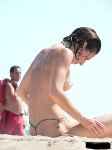 Topless beach milf looking sexy in a tiny g-string bikini