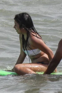 Brunette bikini girl on the beach and surfing in her bikini