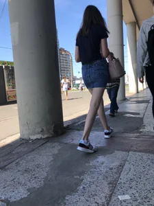 Cute Girl in a Short Denim Skirt Walking on a Street And Waiting on a Crosswalk Gallery