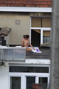 Neighbor on rooftop tanning in bikinis