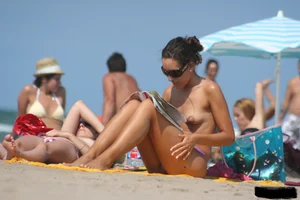 2 topless girls at the beach in thongs