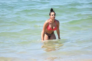 Huge boobed thick brunette babe on the beach in a bikini