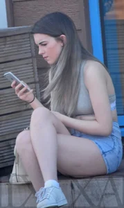 Very Hot Candid Girl in Denim Shorts Sitting With Crossed Legs on the Street With Her Phone Creepshot