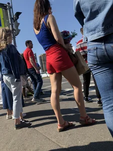 Pretty candid girl wearing red shorts and sandals standing on crosswalk street creepshopt