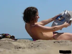Topless beach milf looking sexy in a tiny g-string bikini