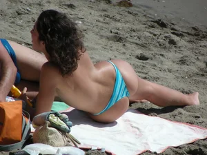 Topless brunette babe on the beach with an incredible bubble butt
