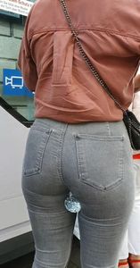 Blond girl in tight grey jeans waiting for the bus