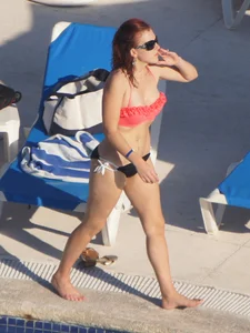 Sexy red haired girl in pink and black bikini at the pool